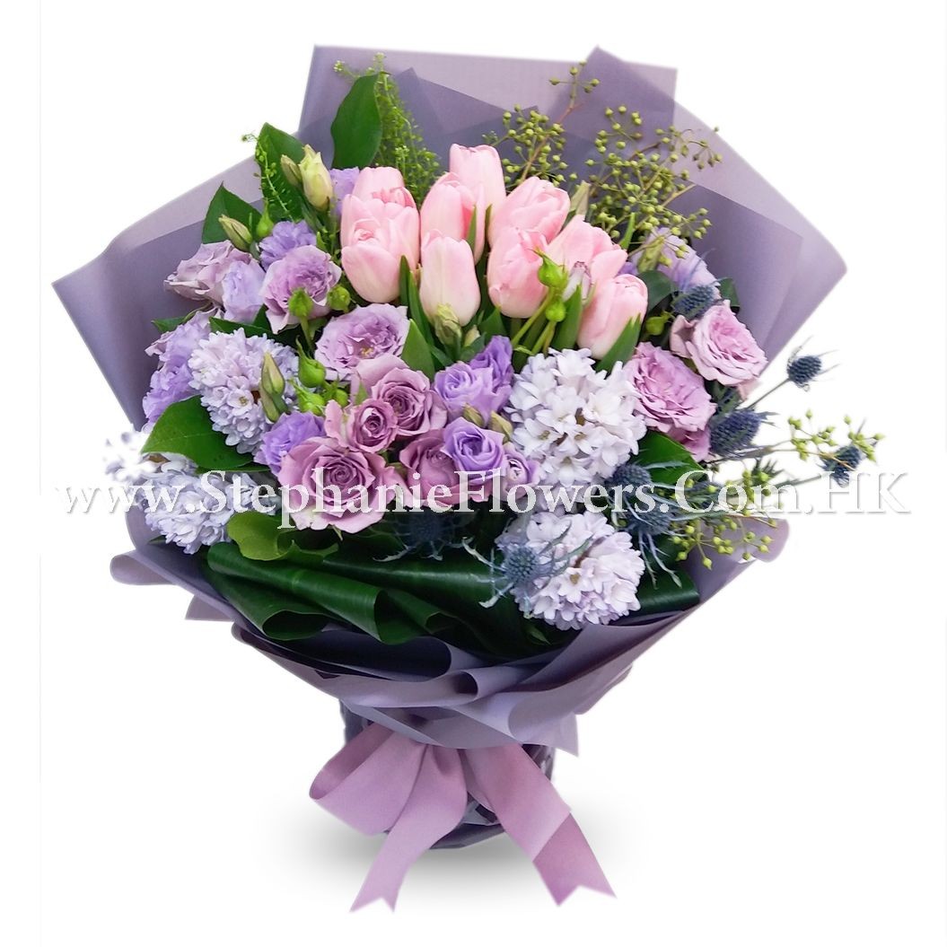 Bouquet of pink tulips and purple roses wrapped in lavender paper with a pink ribbon.